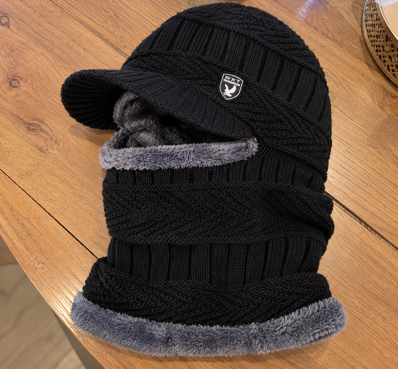 Zwarte balaclava met grijze voering op een houten tafel